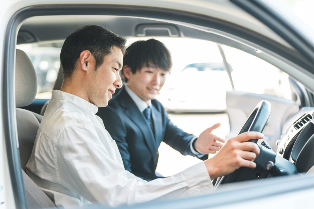 自動車の車内で営業マンの説明を受ける顧客の男性
