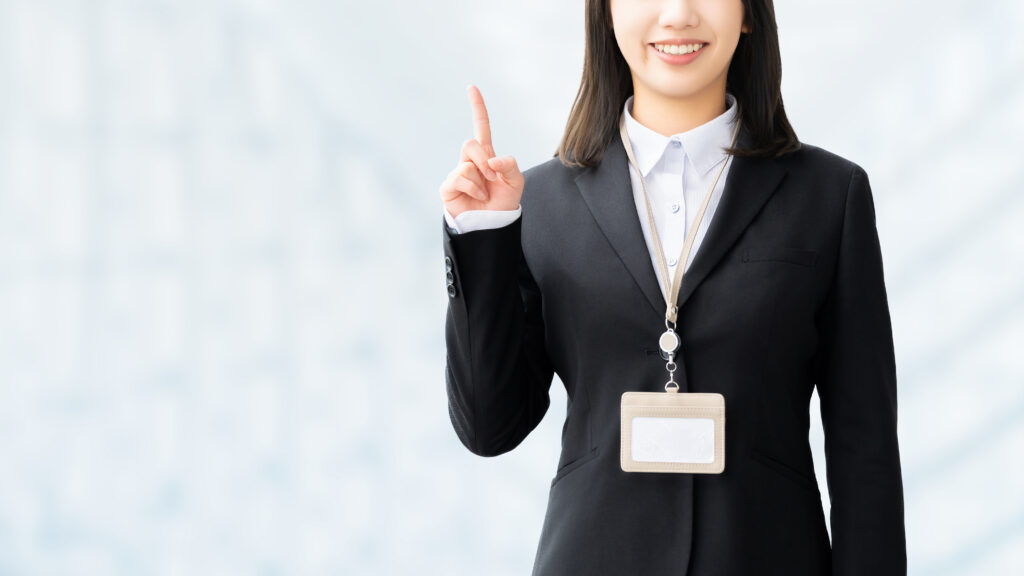人差し指を立てて案内する笑顔の女性・ビジネスウーマン