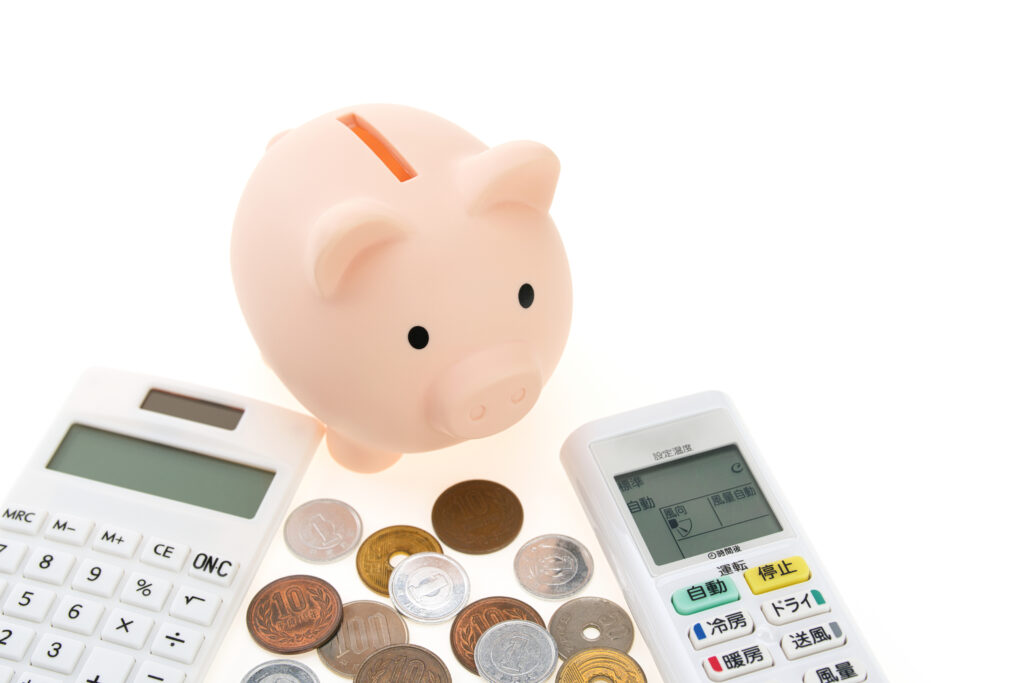 エアコンのリモコンと電卓と豚の貯金箱