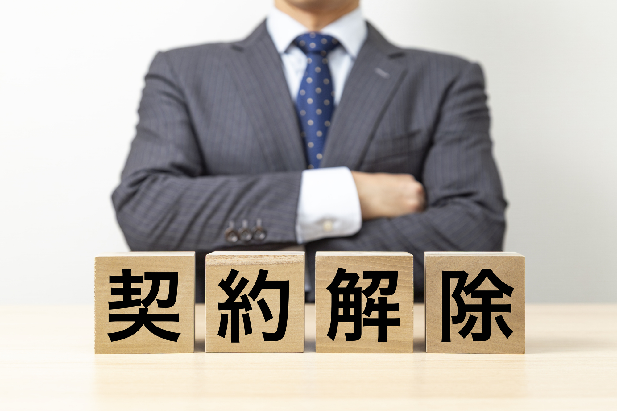 「契約解除」と書かれたブロックと腕組みをするビジネスマン