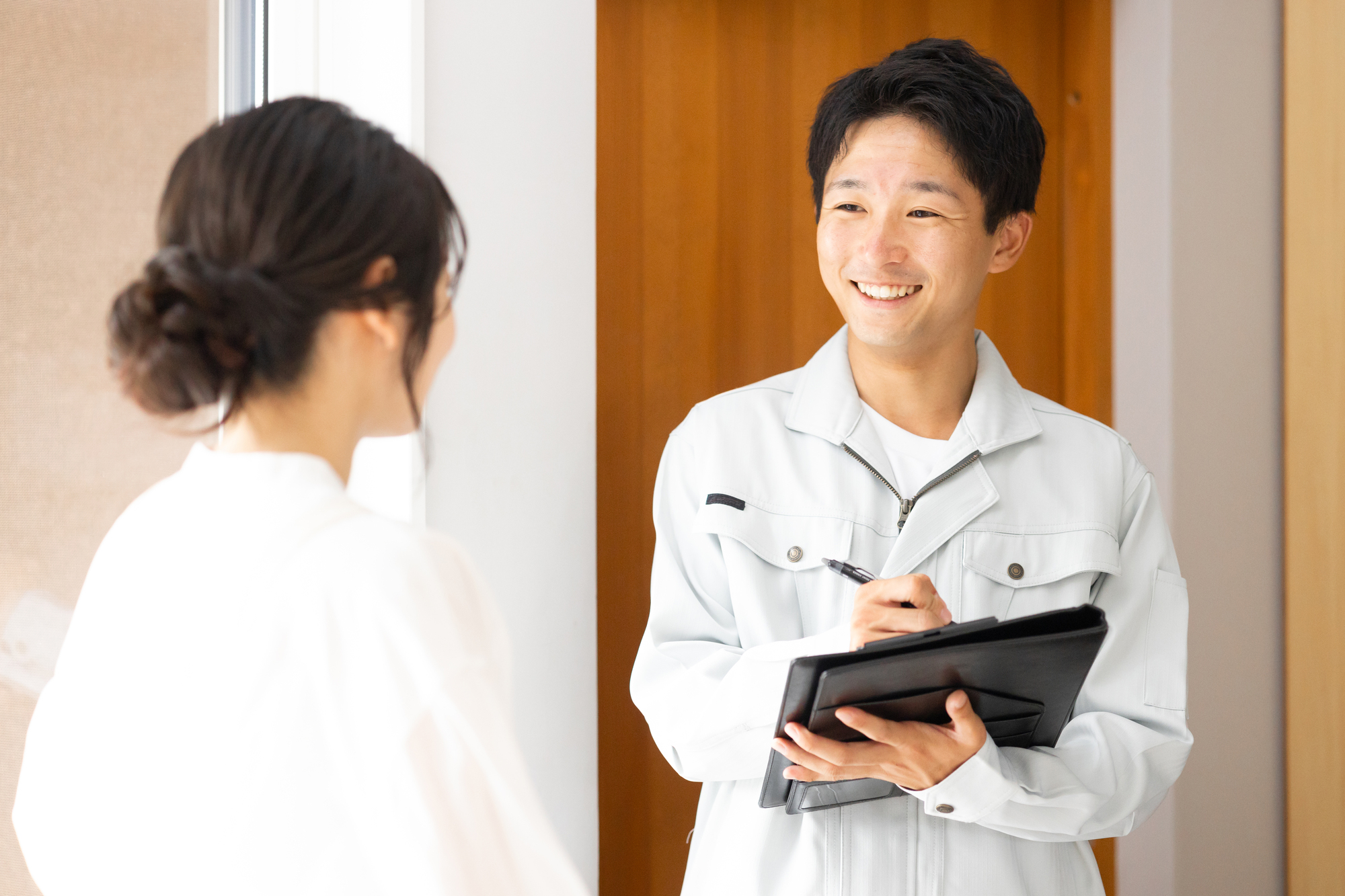 作業着姿の男性の話を聞く主婦