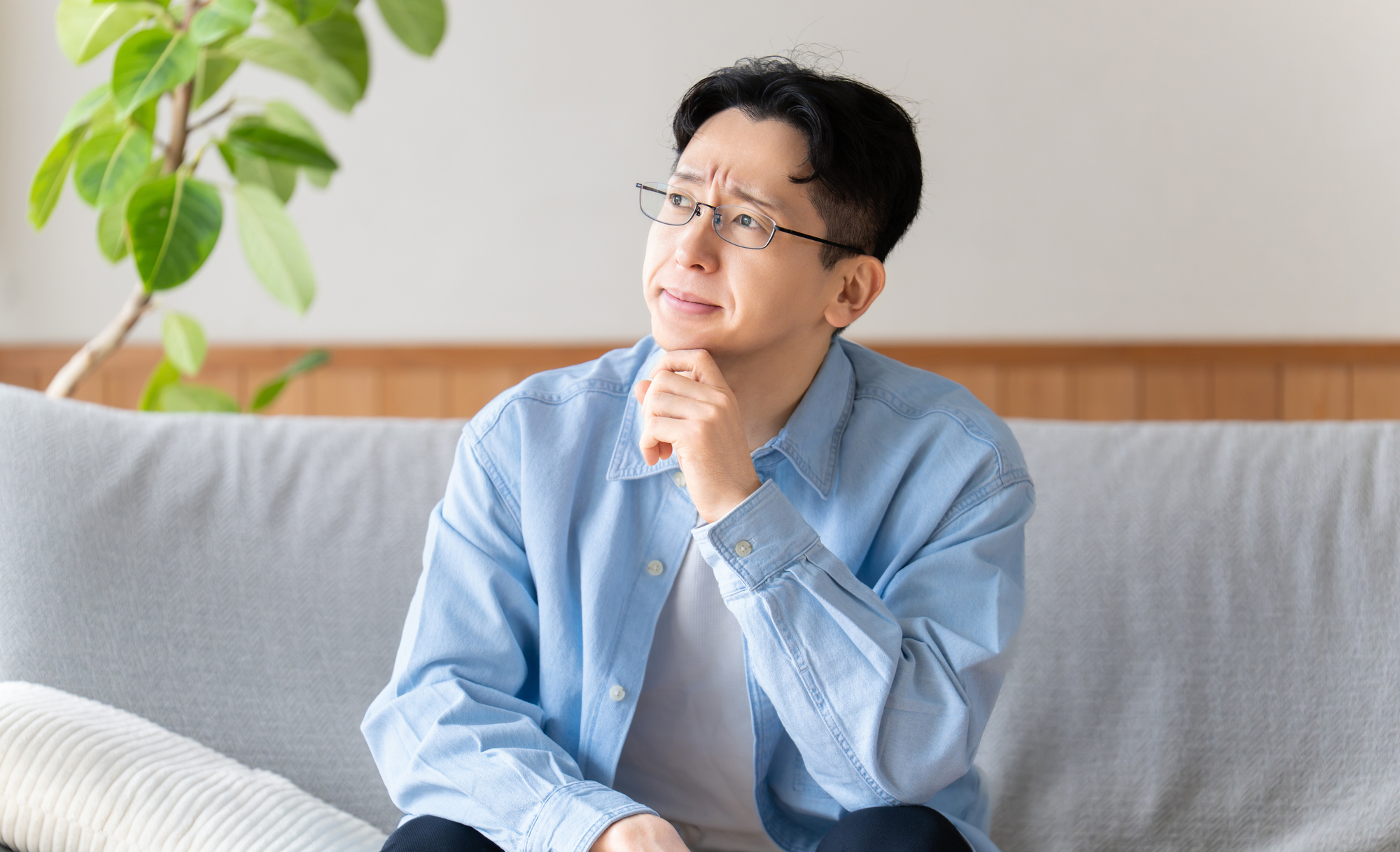 ソファに座って考える男性