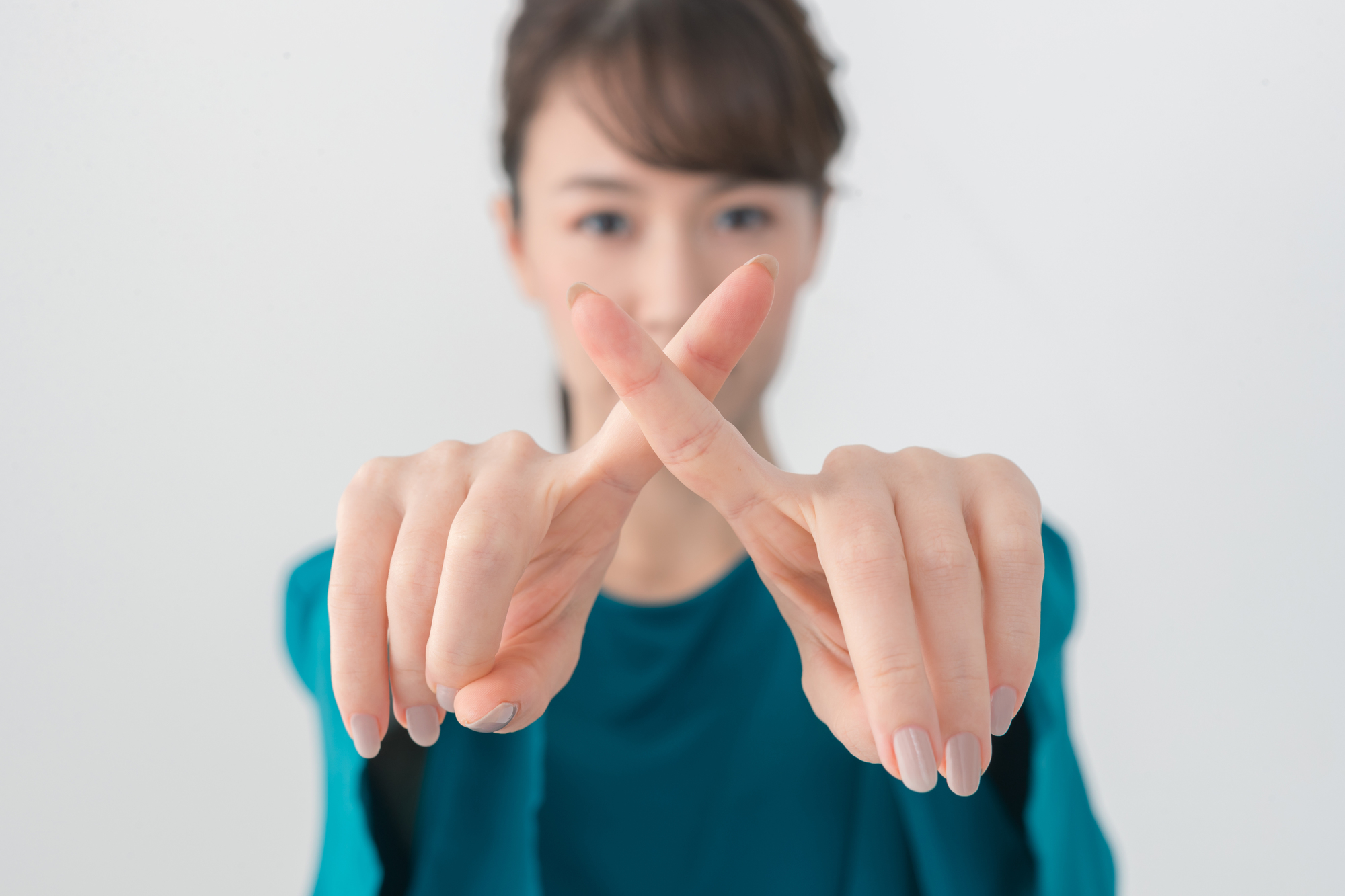 指で×を作る女性
