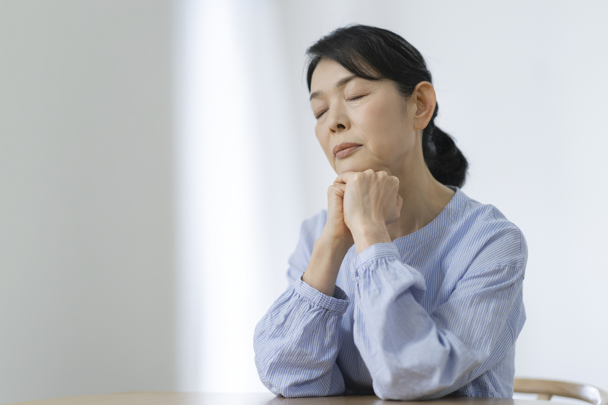 両手に顎を乗せて悩むの女性