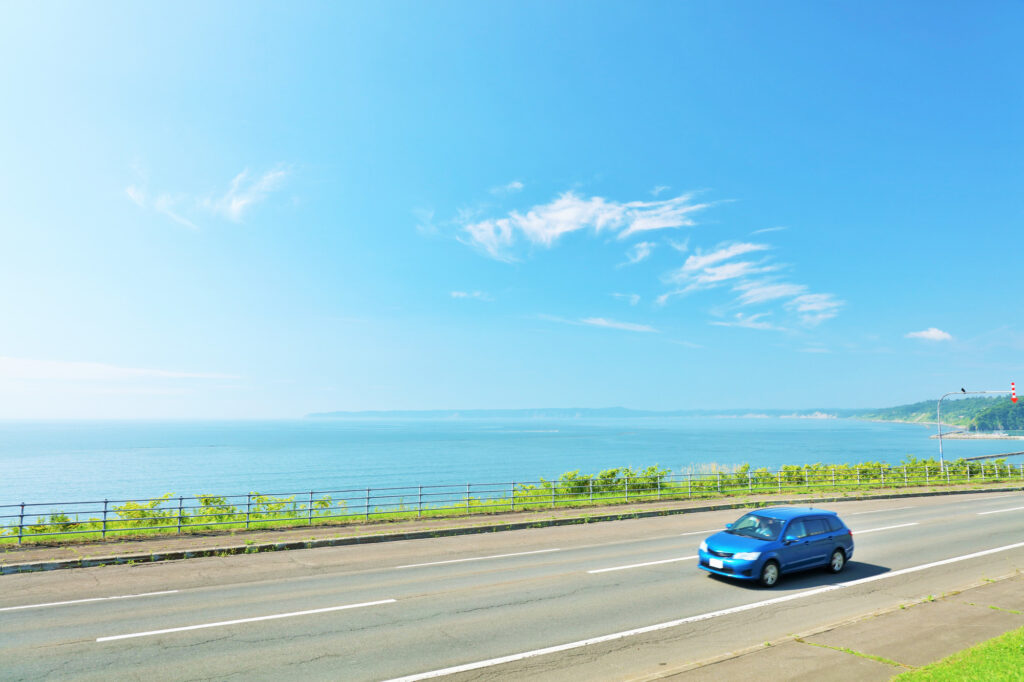 青空と海沿いの道を走る車