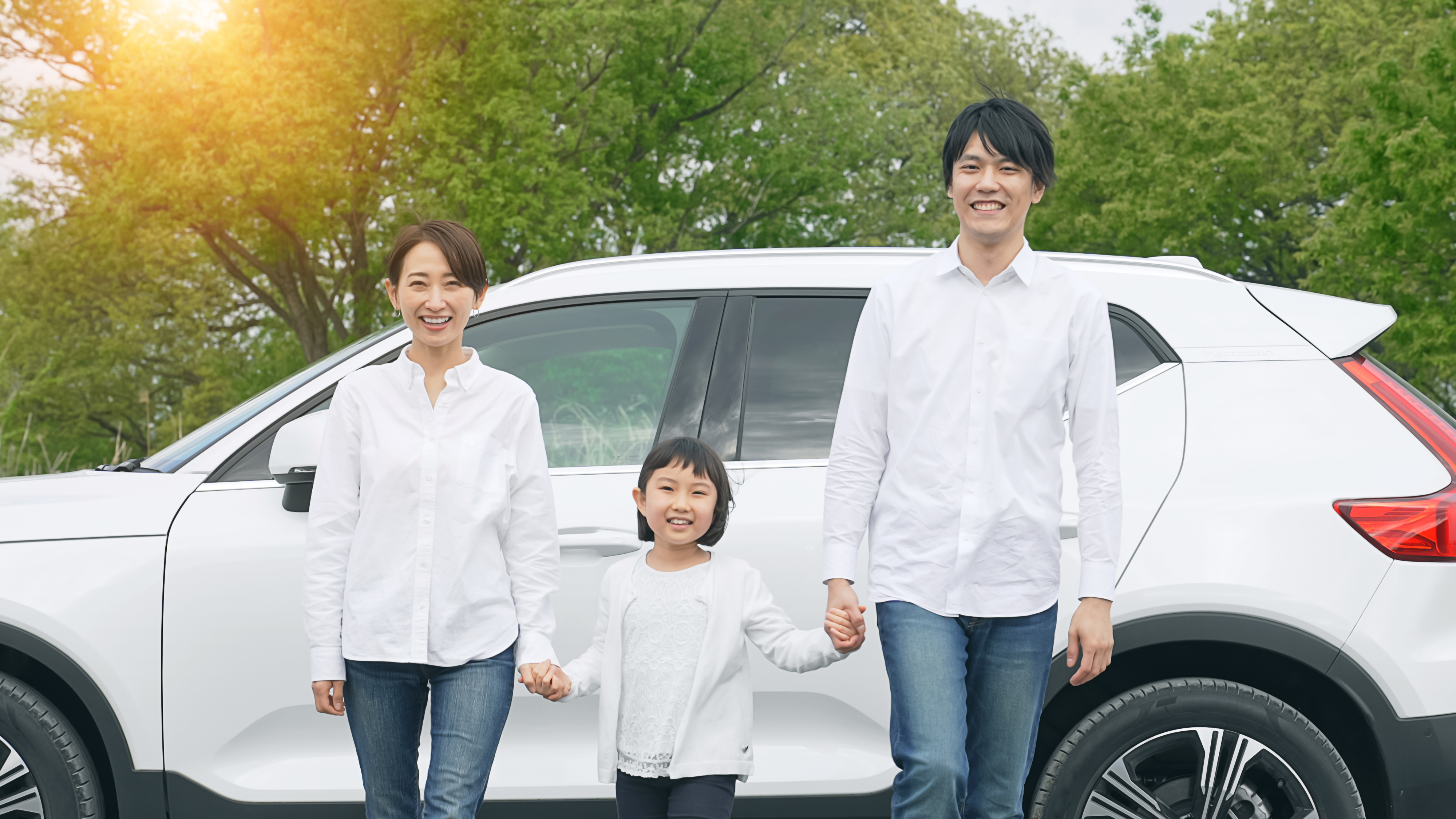 車の前で手を繋ぐ家族